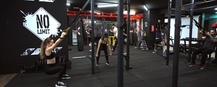 Gente entrenando en un gimnasio moderno con equipos de ejercicio y ambiente motivador.