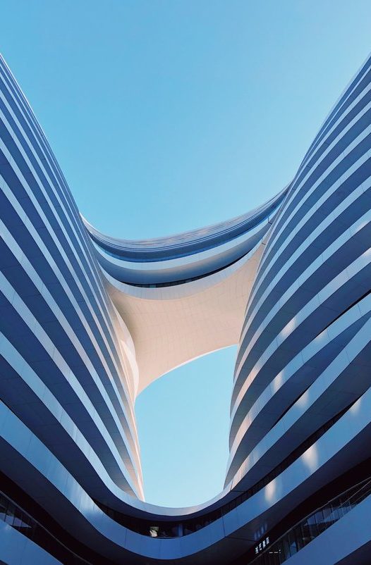 Edificios modernos, con diseño curvado y cielo azul de fondo.